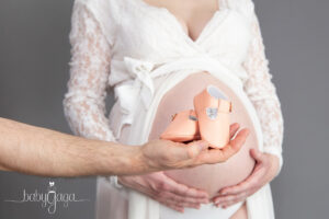 Douce photo du ventre d'une femme enceinte avec les souliers du futur bébé